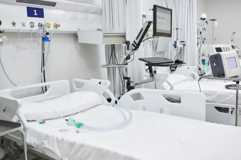Empty hospital ward beds with monitoring equipment