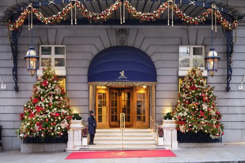 Decorated hotel entrance with doorman, Christmas trees and red carpet